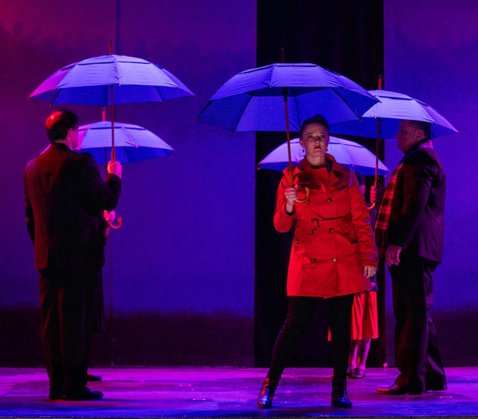 Actors on stage with umbrellas