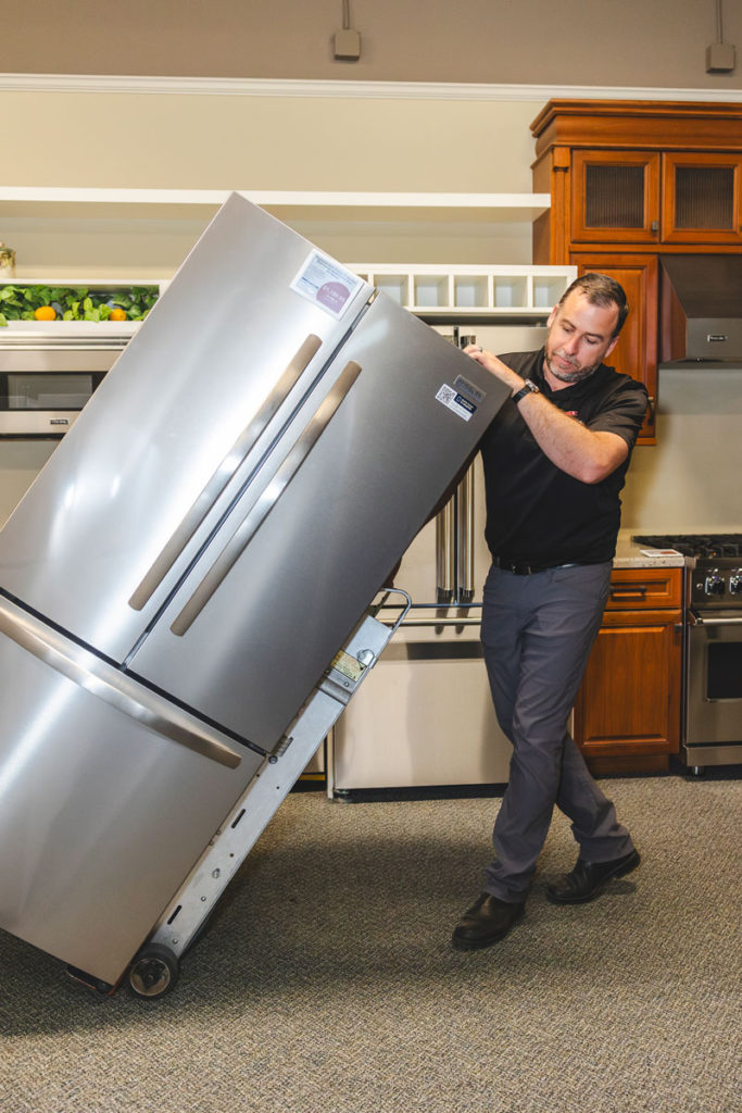 A TeeVax employee moving a refrigerator